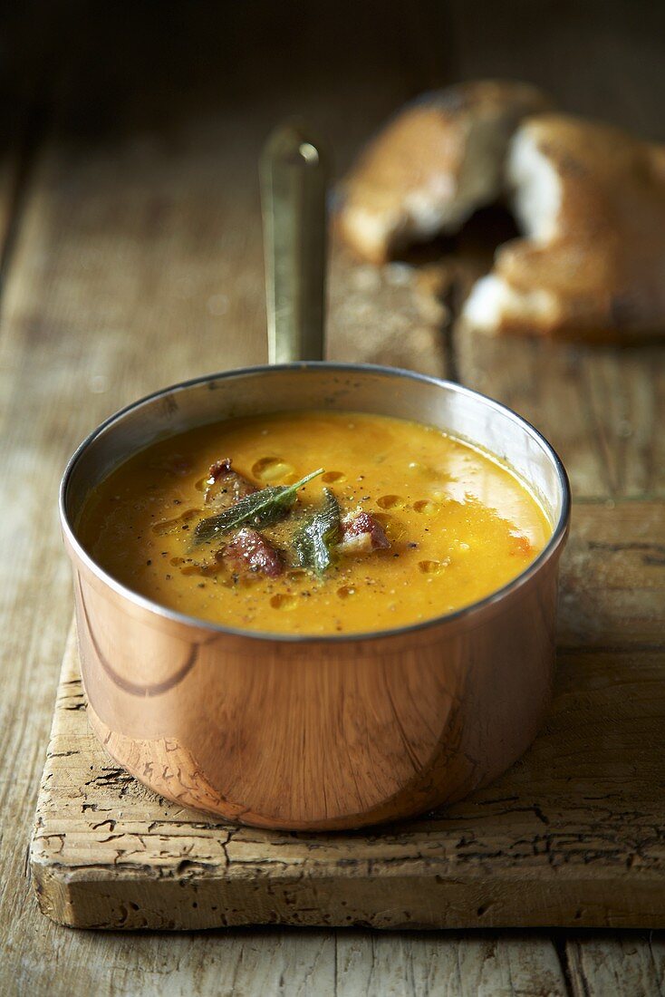 Pumpkin soup with sage and bacon in copper pan