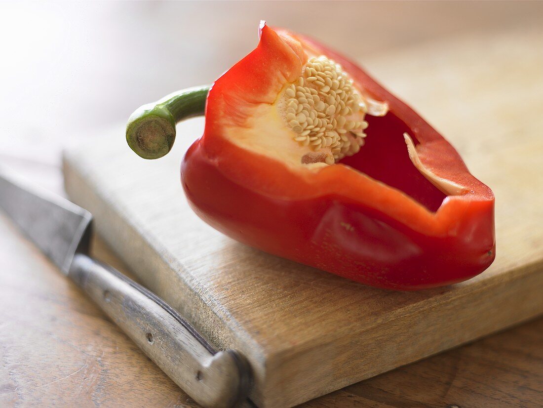 Red pepper with a section removed on chopping board