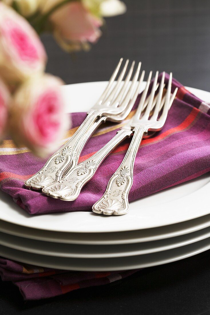 Forks and fabric napkins on pile of plates