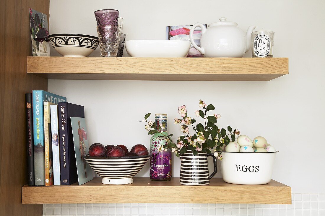 Crockery, books, fruit and eggs on kitchen shelves