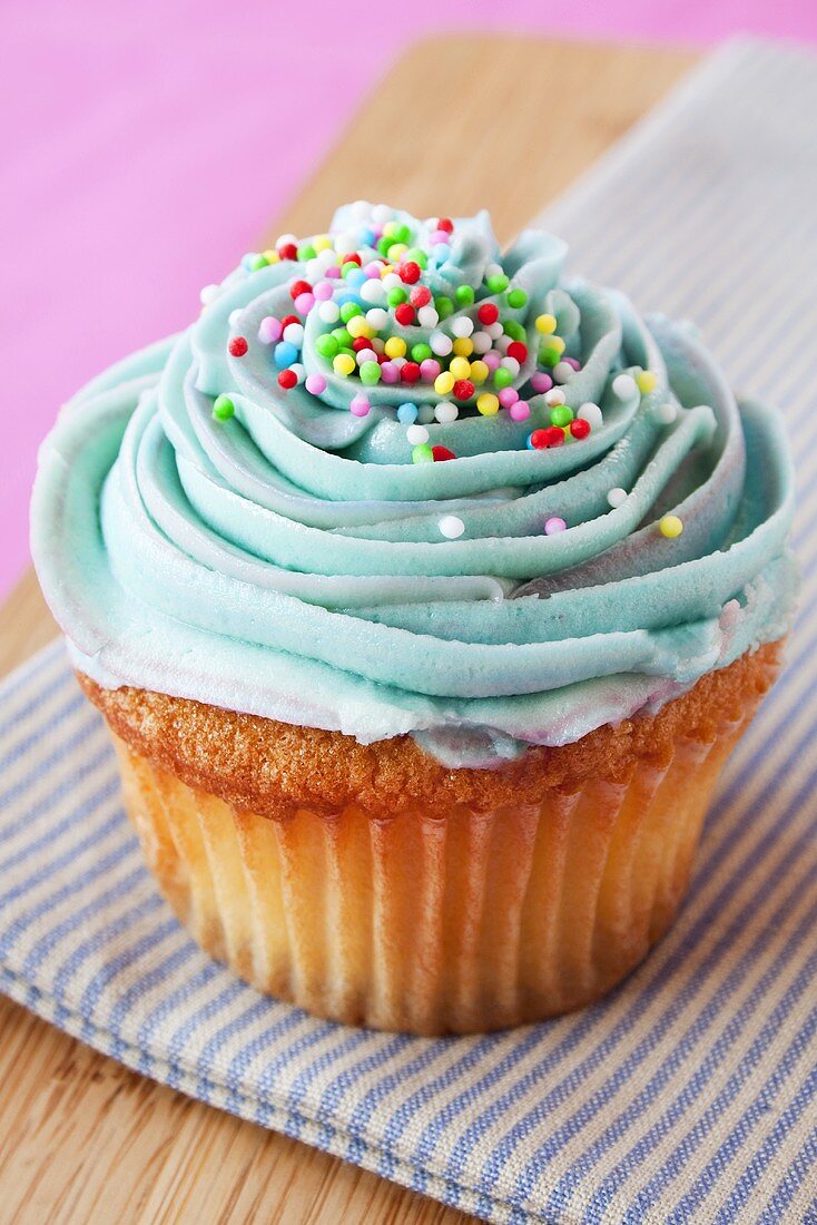 Cupcake mit blauer Glasur und bunten Zuckerperlen