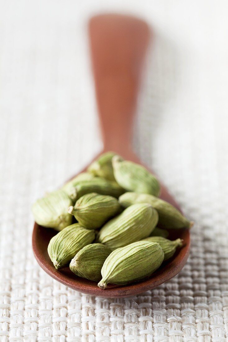 Cardamom pods on wooden spoon