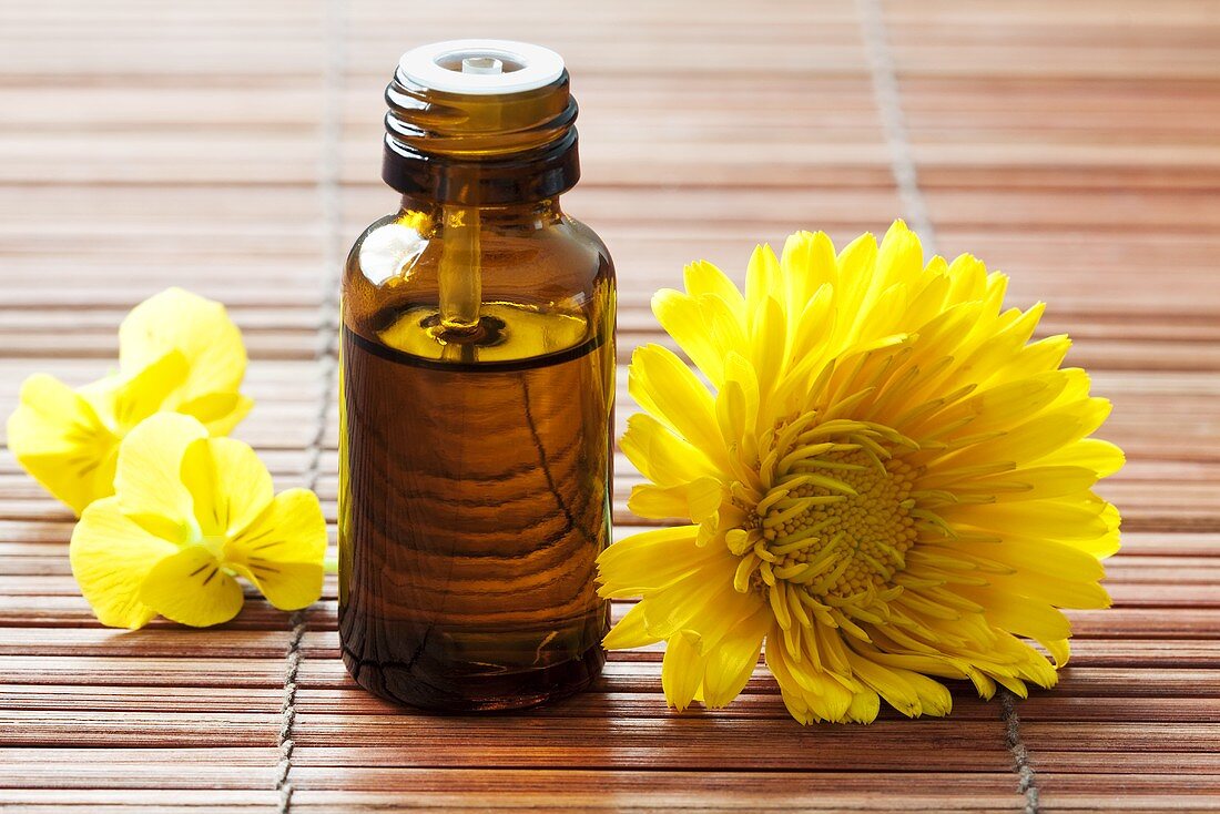 Aromatherapie: Ölfläschchen und gelbe Blüten