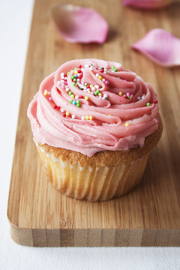 Cupcake mit rosa Glasur und bunten Zuckerperlen