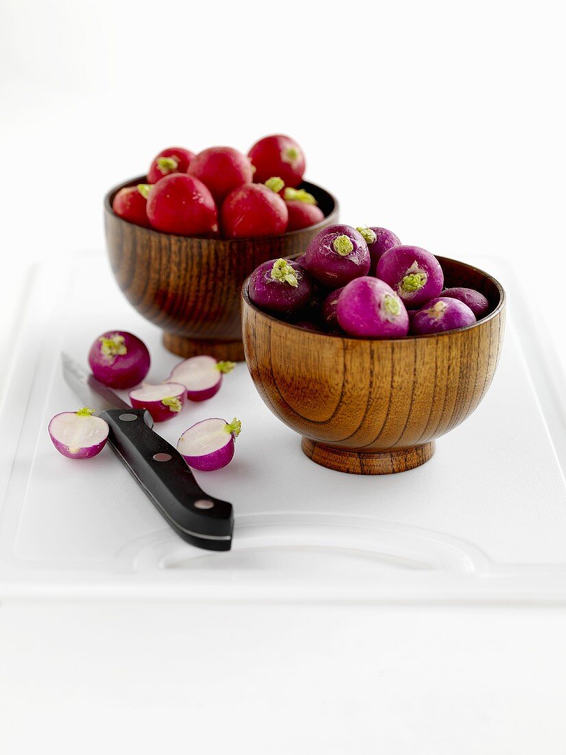 Radishes in wooden bowls on chopping board