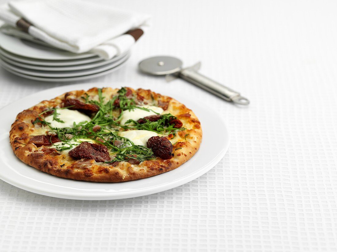 Pizza mit getrockneten Tomaten, Mozzarella und Rucola