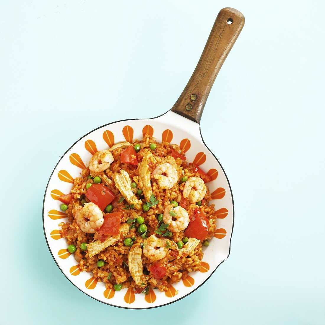 Paella with chicken and prawns in frying pan from above