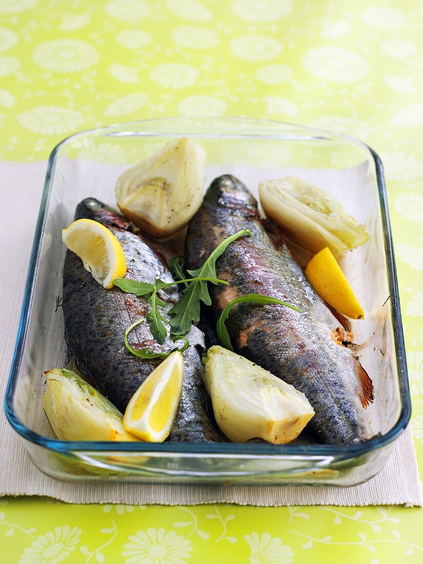 Baked trout with artichokes in glass baking dish