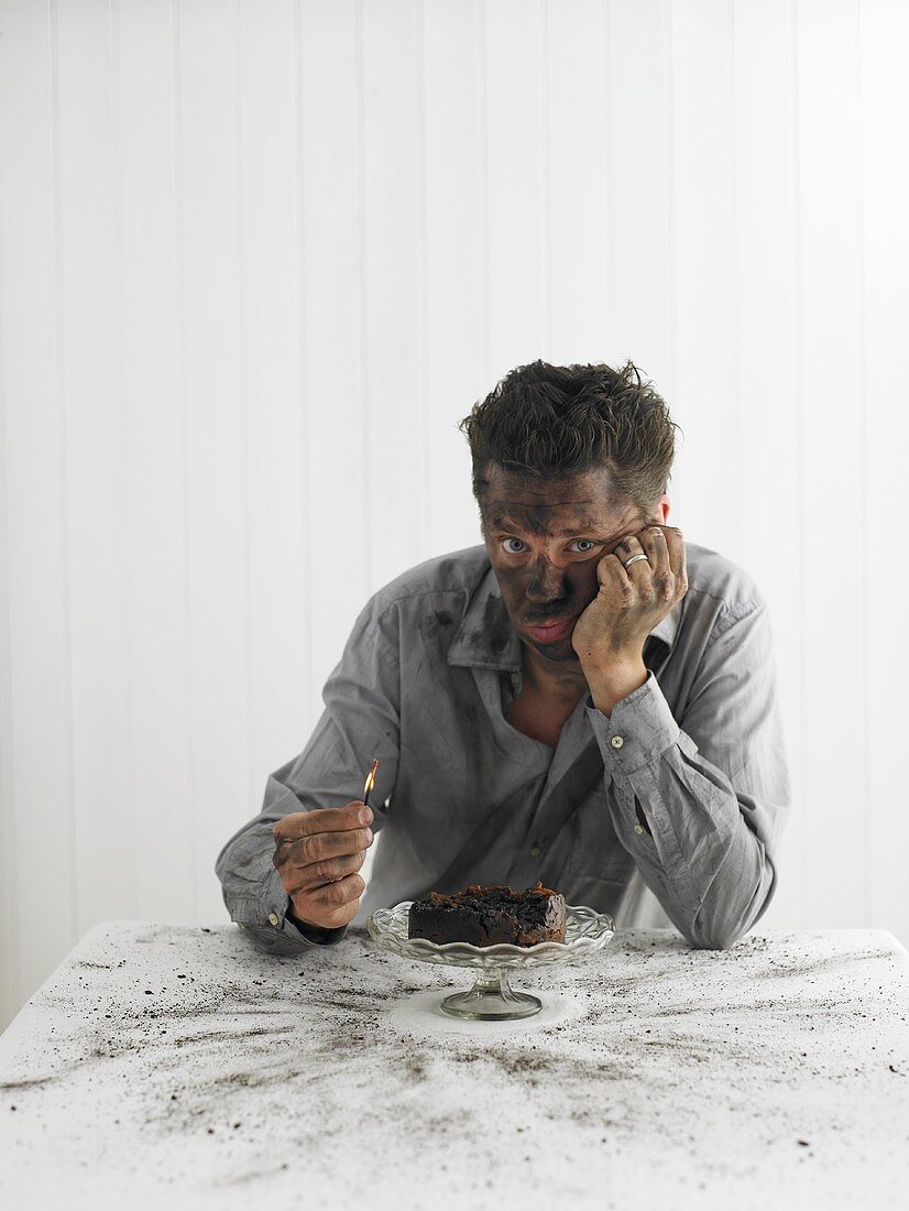 Man with match sitting in front of exploded Christmas pudding