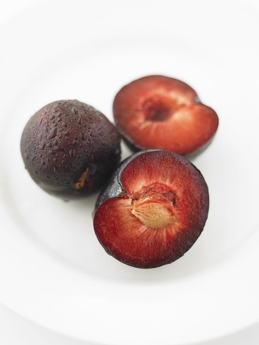 A whole plum with two plum halves