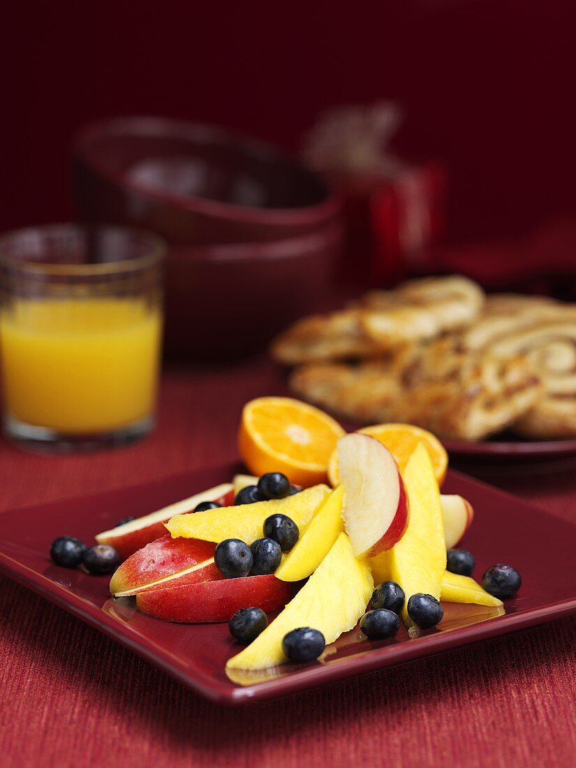 Frische Früchte, süsses Gebäck und Orangensaft zum Frühstück
