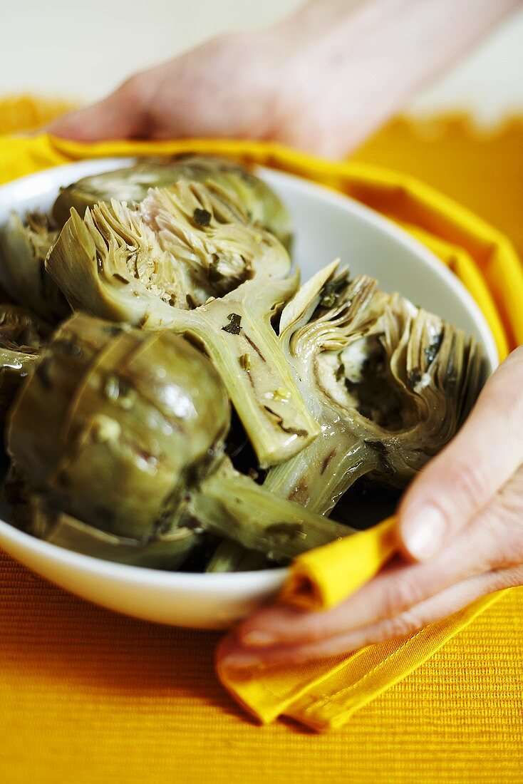 Woman holding a bowl with steamed artichokes