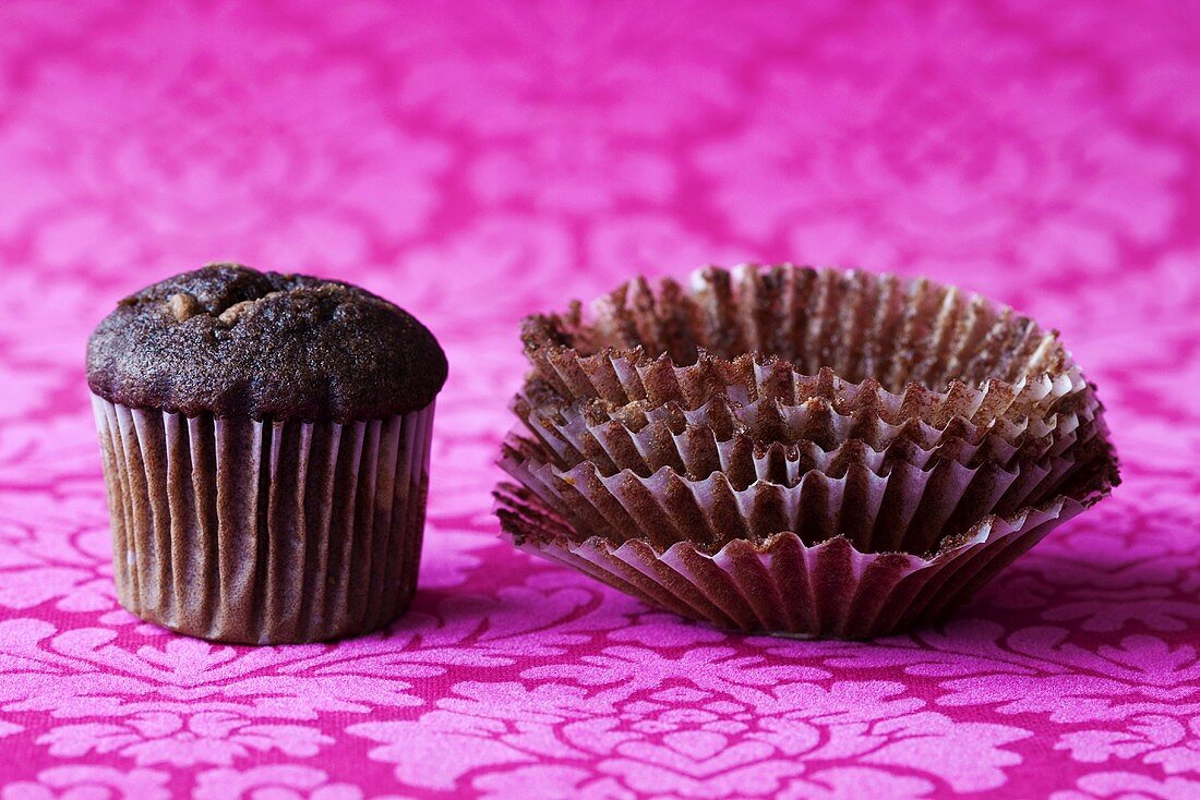 Chocolate muffin and empty paper cases