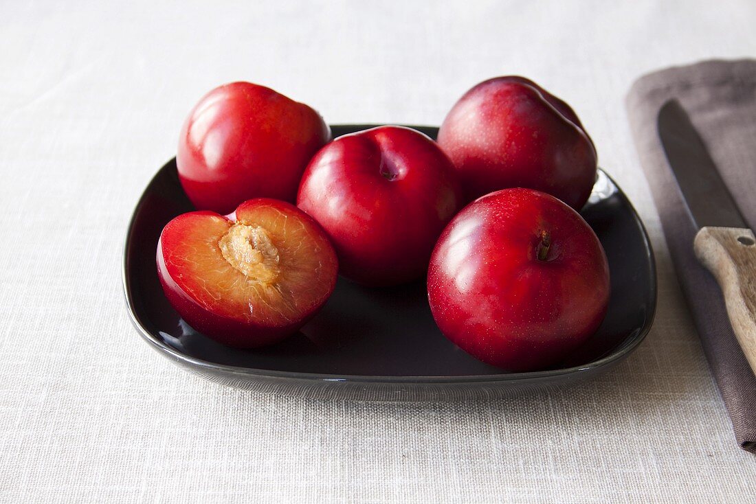 Red plums, whole and halved, on plate