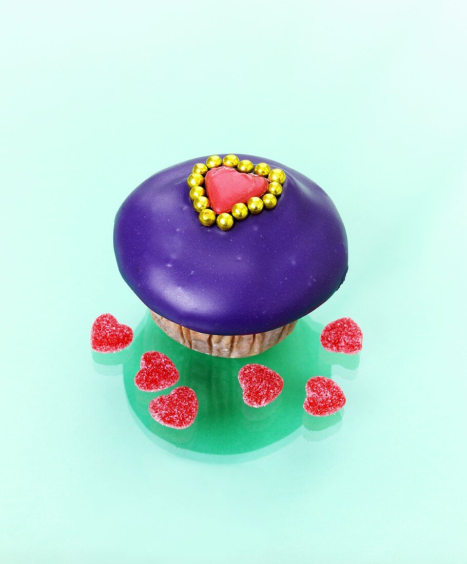 Muffin mit lila Zuckerguss und Fruchtgummi-Herzen
