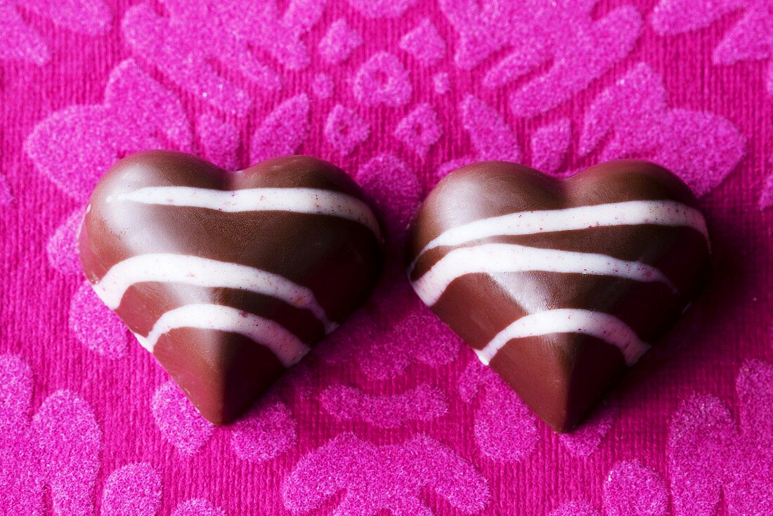 Two chocolate hearts on purple background