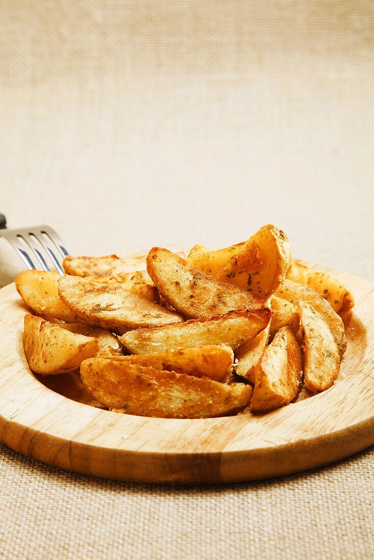 Deep-fried potato wedges on wooden plate