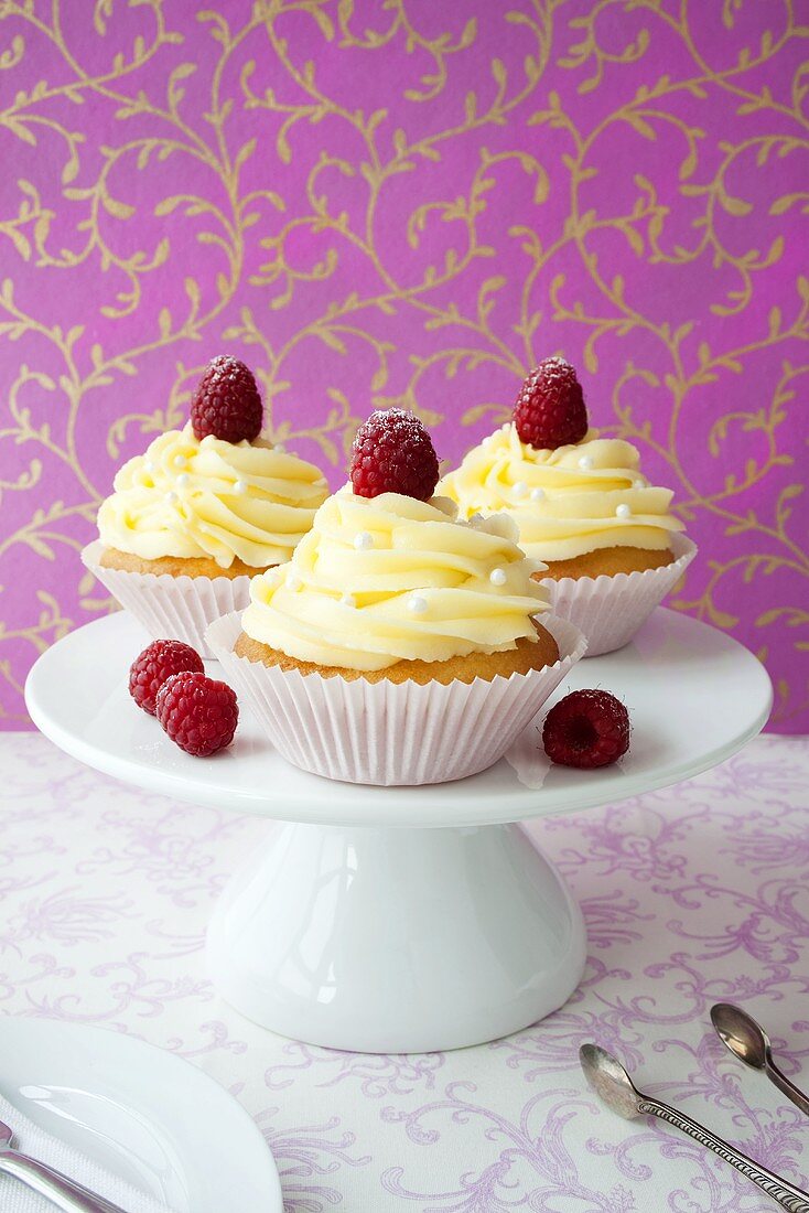 Cupcakes with buttercream and raspberries on cake stand