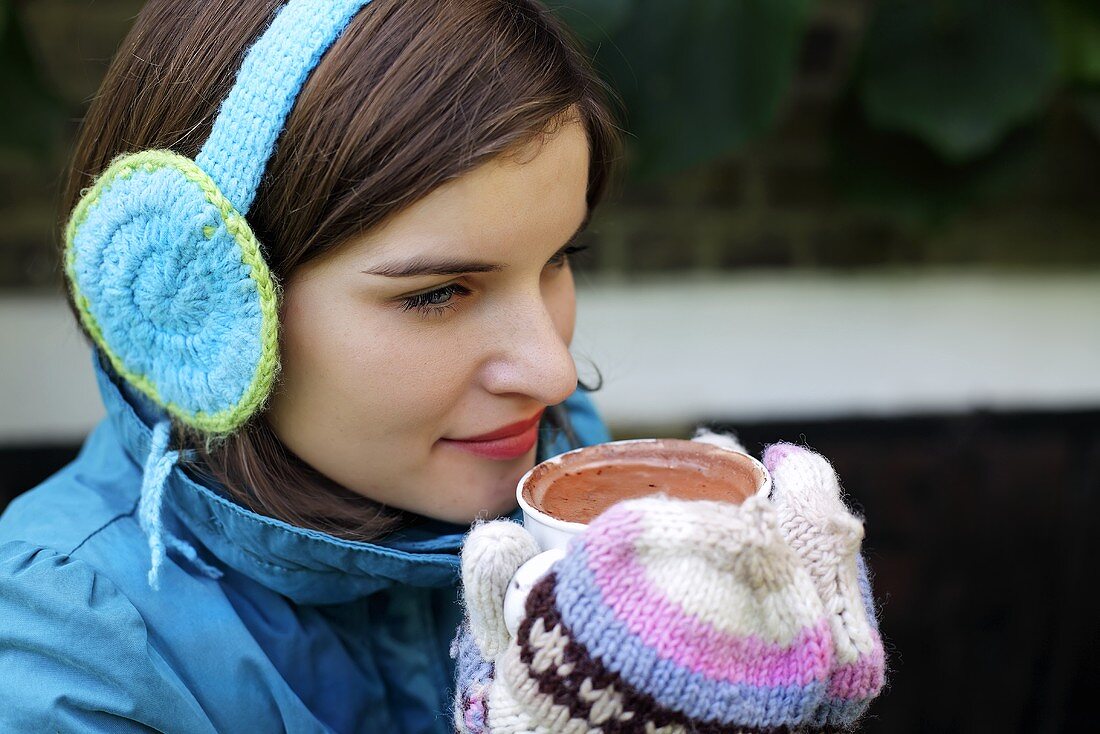 Junge Frau hält eine Tasse mit heißer Schokolade