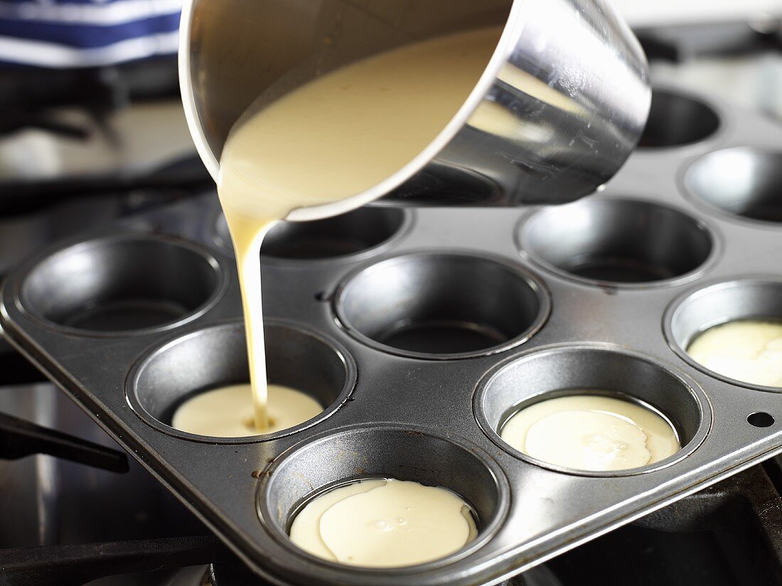 Pouring Yorkshire pudding mixture into a muffin tin