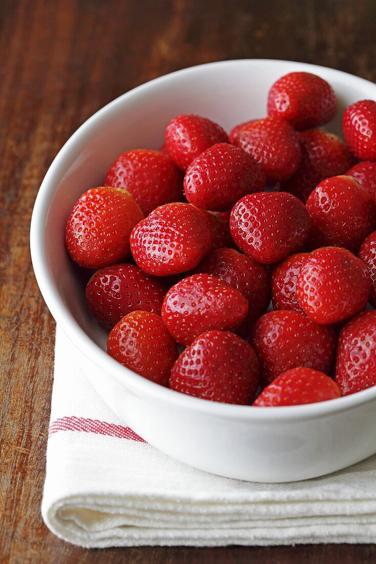 A bowl of strawberries on a tea towel