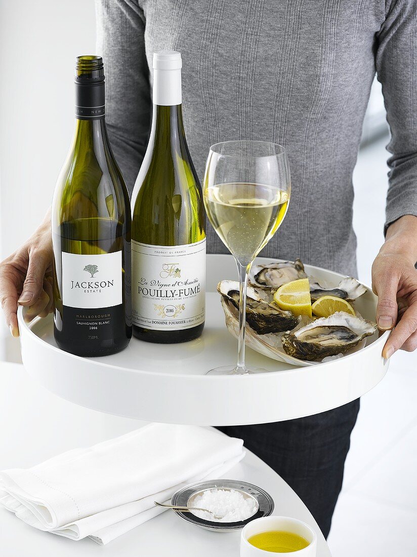 Woman serving tray of white wine and oysters