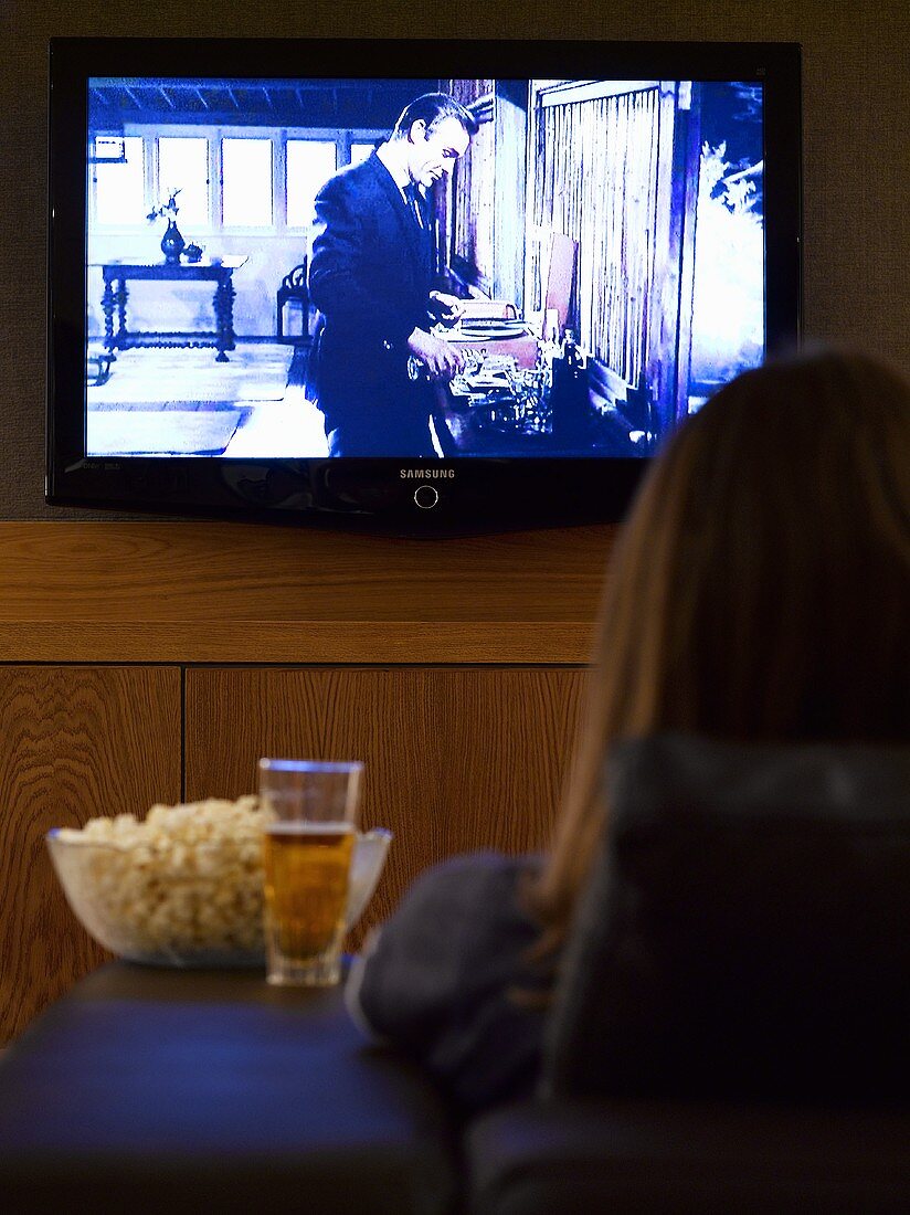 Woman with beer and popcorn in front of TV