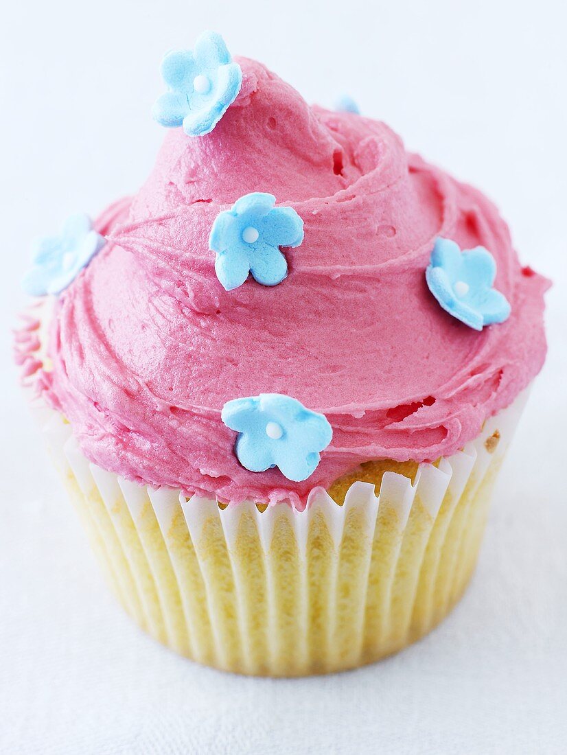 Cupcake mit rosa Zuckercreme und Zuckerblüten