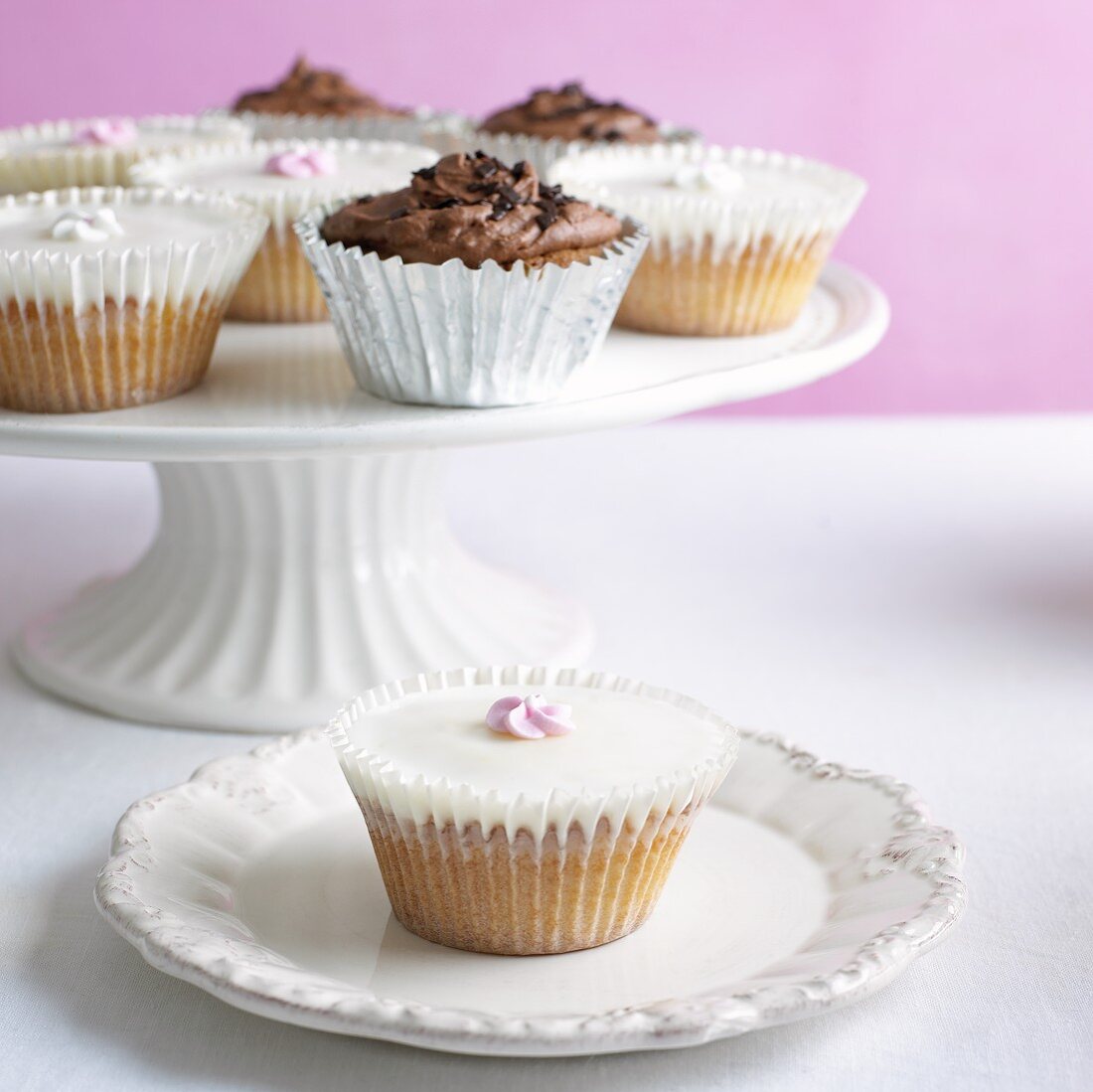 Verschiedene Cupcakes auf Kuchenständer und Teller