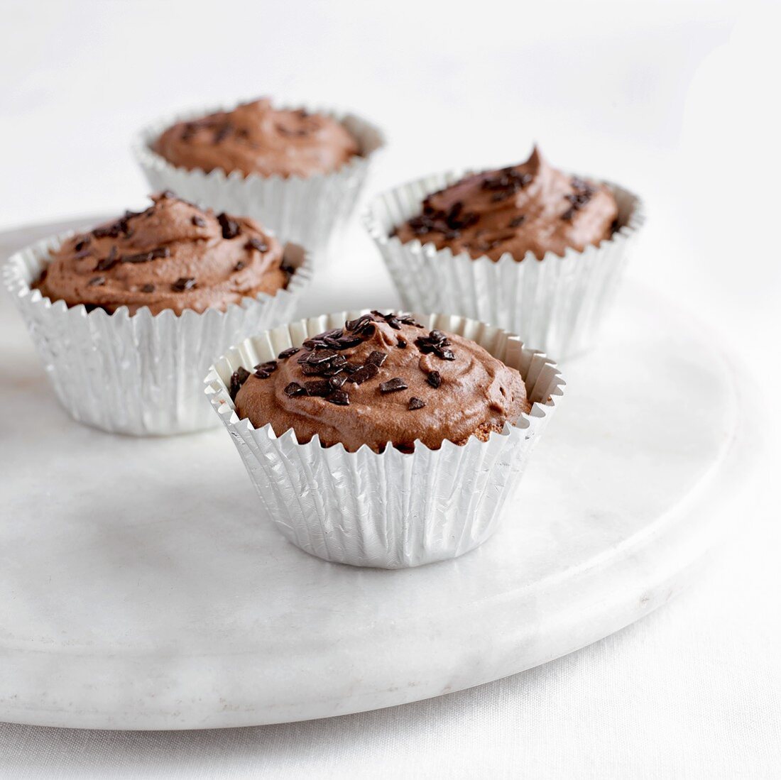 Four chocolate cupcakes on marble plate