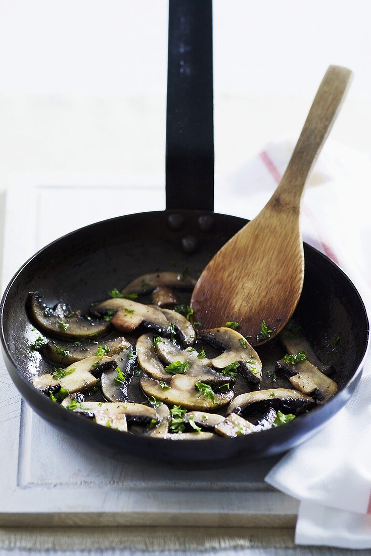 Fried mushrooms with parsley in frying pan