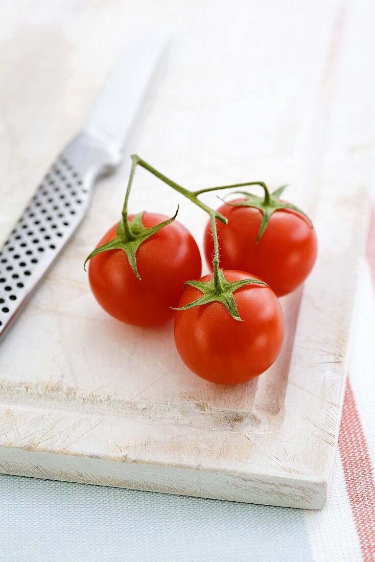 Drei Kirschtomaten auf Schneidebrett