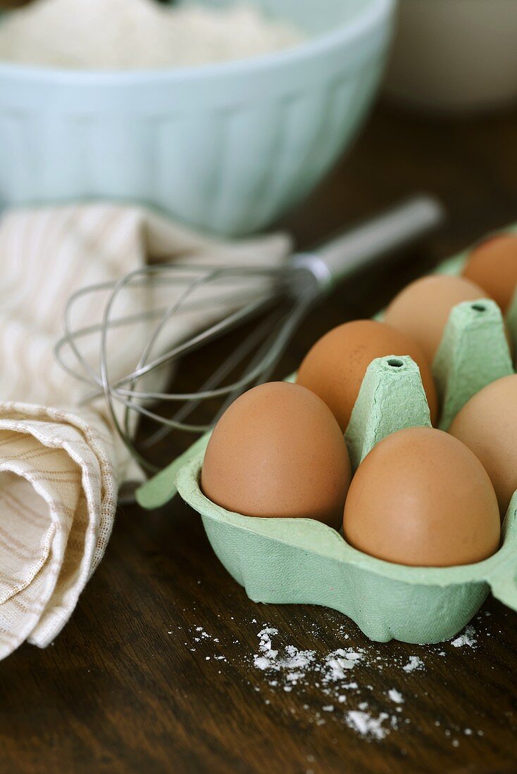 Eier im Eierkarton, Schneebesen, Geschirrtuch