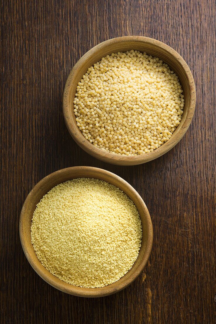 Two different sorts of couscous in bowls on wooden background