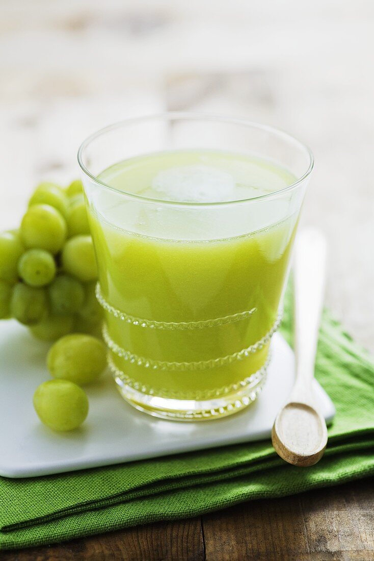 Kiwi fruit and grape juice in glass on small board
