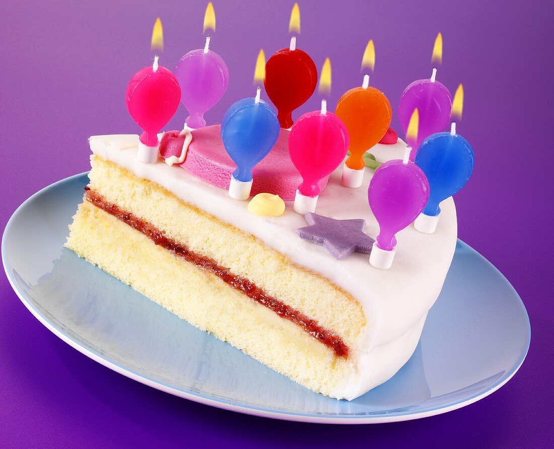 A piece of birthday cake with balloon-shaped candles