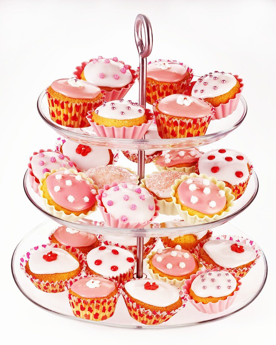 Lots of fairy cakes, decorated in pink and white, on a cake stand