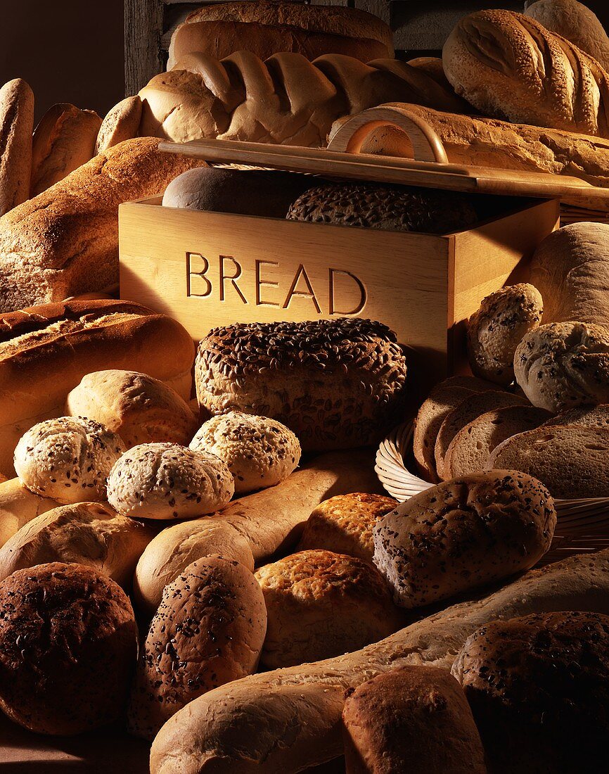 Various types of breads and rolls with a bread bin