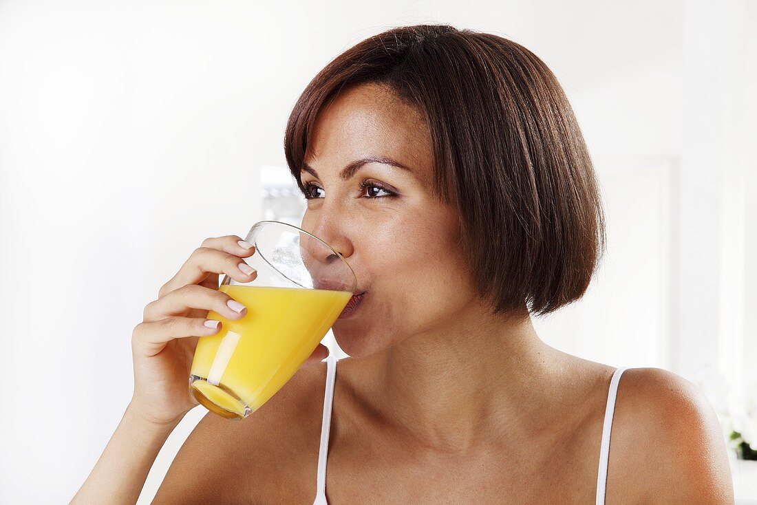 Young woman drinking orange juice, close-up