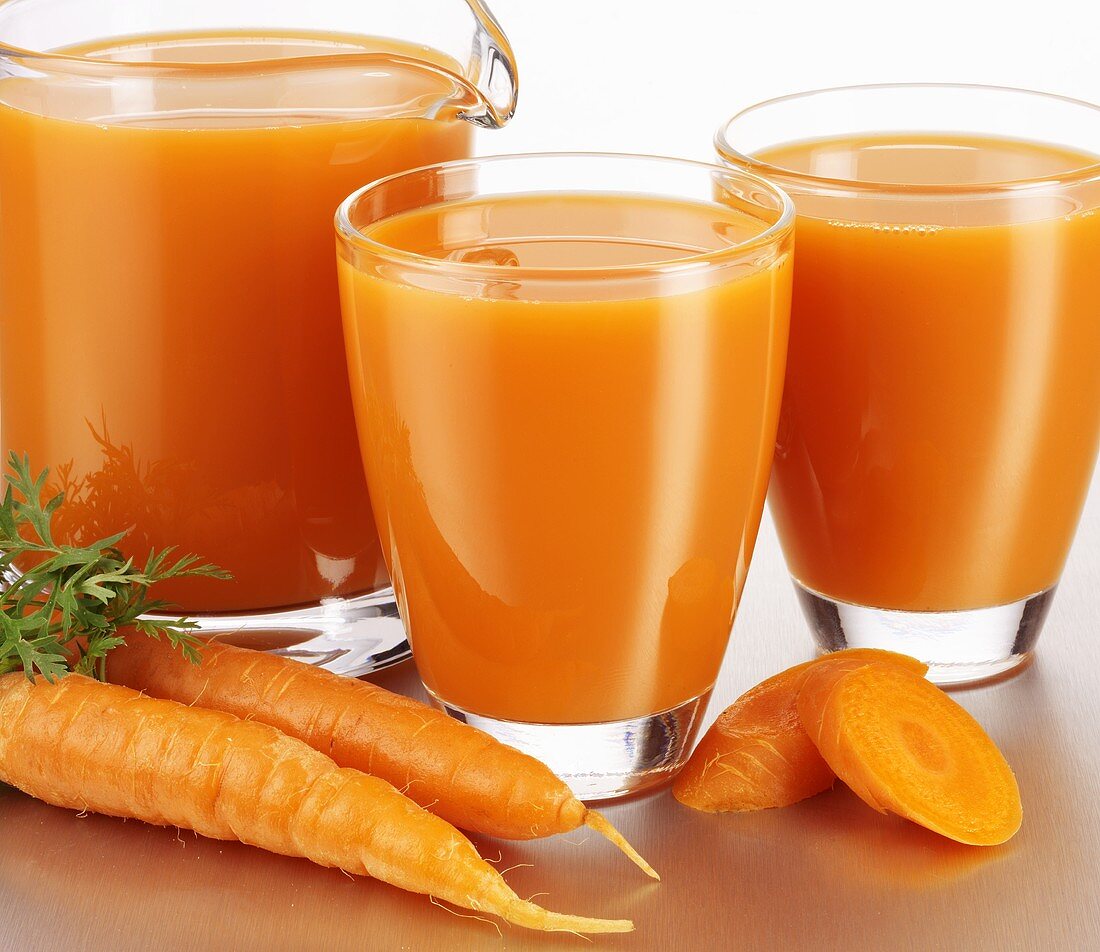 Carrot juice in glasses and a glass jug