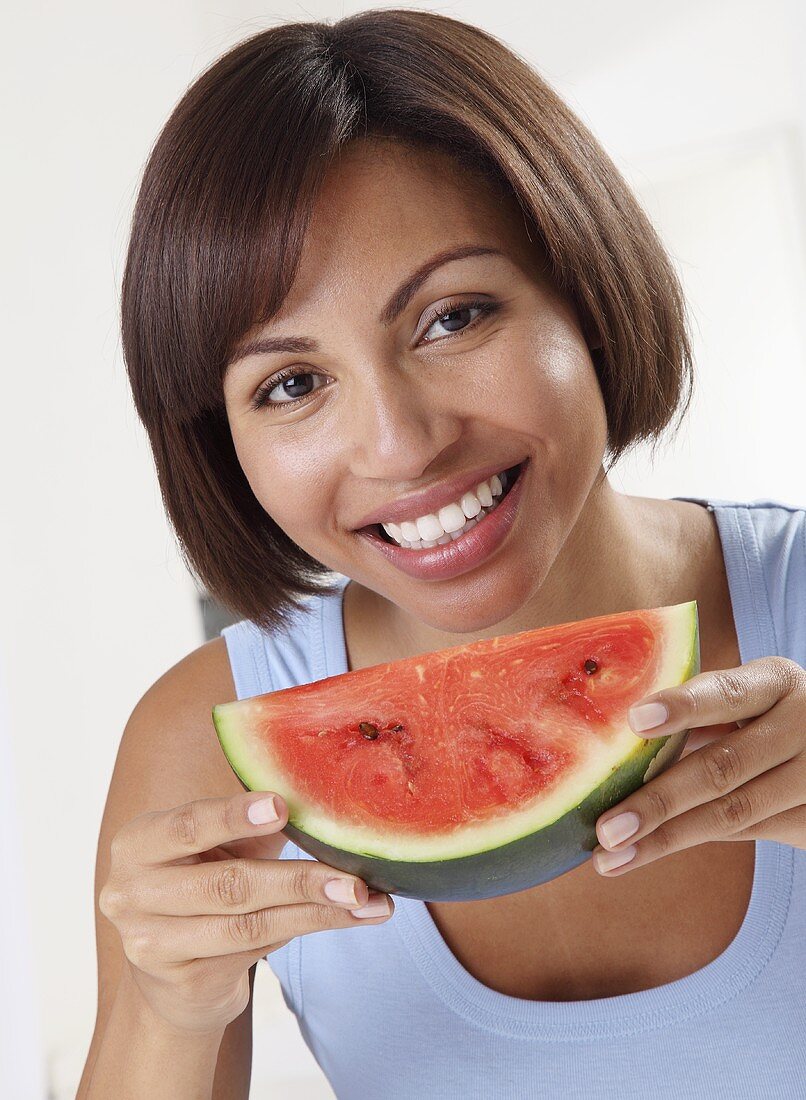 A woman holding a slice of watermelon