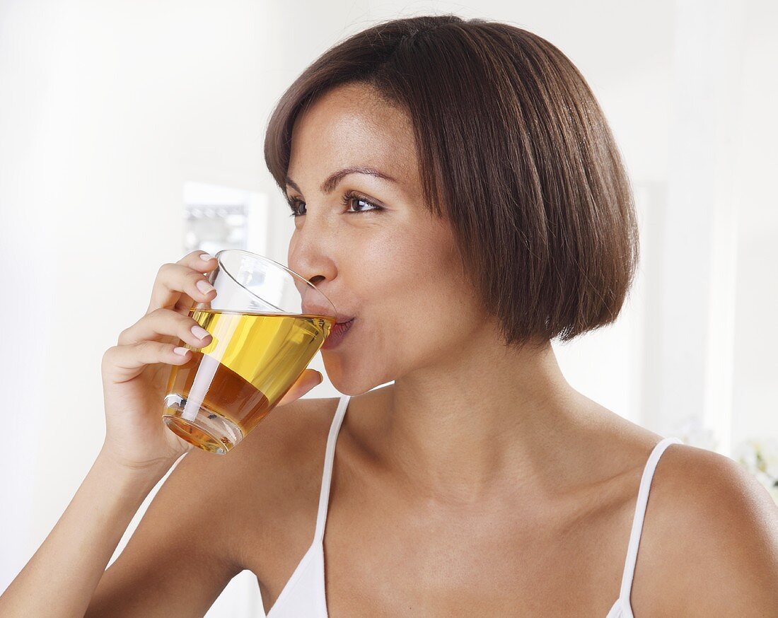 A woman drinking a glass of apple juice