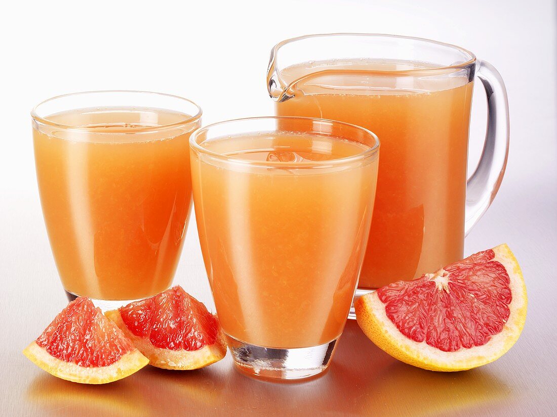 Pink grapefruit juice in glasses and a glass jug