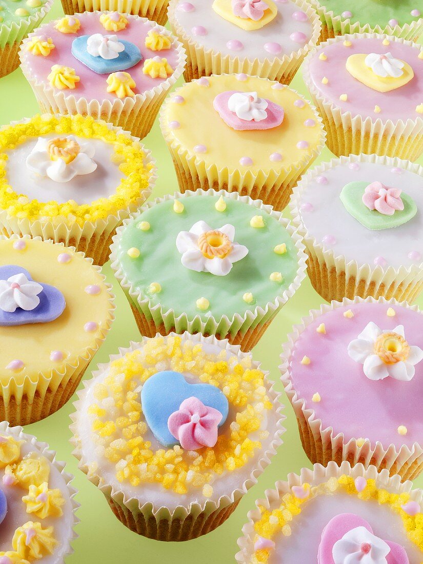 Viele pastellfarbene Cupcakes mit Zuckerblumen