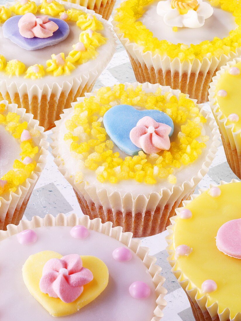 Pastel-coloured fairy cakes with sugar flowers