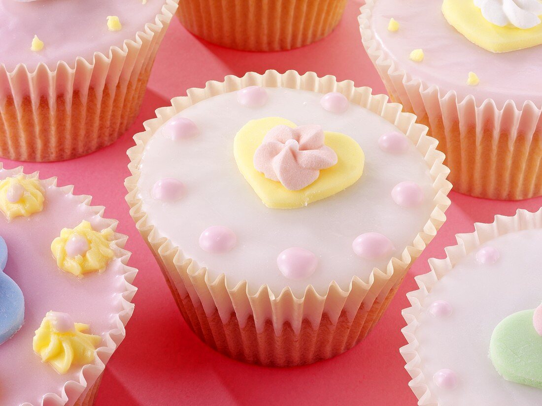 Pastel-coloured fairy cakes decorated with sugar flowers