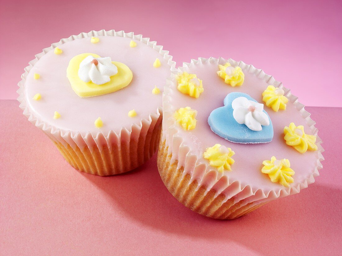 Fairy cakes with pink icing, heart-shaped decorations and sugar flowers