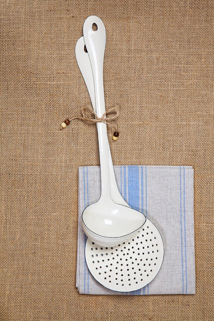 An enamel ladle and a slotted spoon on a dish cloth