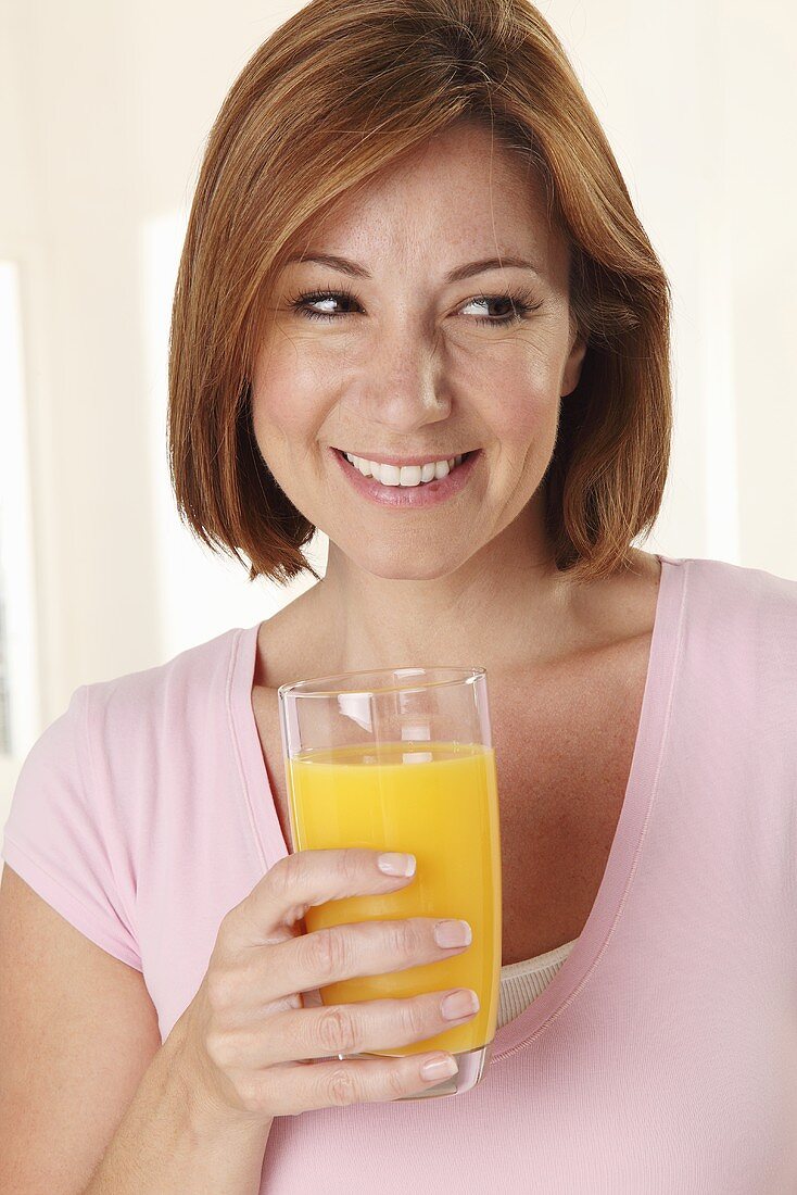 A smiling woman holding a glass of orange juice
