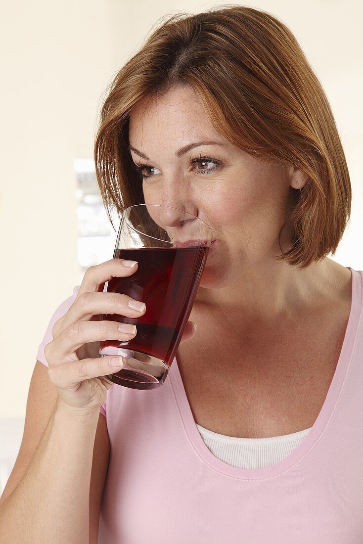 A woman drinking a glass of fruit juice